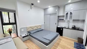A compact bedroom with a bed, bedside table, and a small desk.