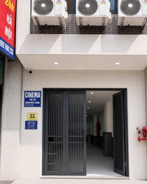 Entrada de cinema amb façana de rajola, una porta metàl·lica i aparells d'aire condicionat a la part superior.