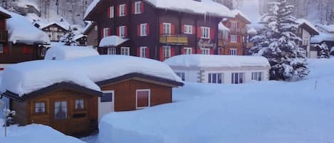 A snow-covered village with wooden buildings and a mountain backdrop.