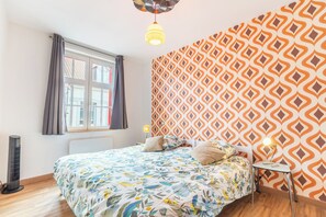 A bedroom with a bed, a window, a radiator, and a patterned wall. - The red house Béthune - 2 minutes from the main square (Béthune)