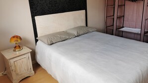 A bedroom with a bed, a nightstand with a lamp, a wardrobe, and a patterned wall. - House in the heart of the village (Chevanceaux)