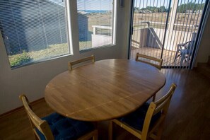 A round wooden dining table with four chairs, positioned near a window with blinds. - Mare Vista (TOT # 2194): 2  BR, 2  BA House in The Sea Ranch, Sleeps 4 (The Sea Ranch)