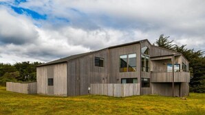 En moderne bygning med to etager, fladt tag, store vinduer og en balkon på øverste etage.