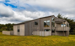 A modern two-story building with a flat roof, large windows, and a balcony on the upper level. - Mare Vista (TOT # 2194): 2  BR, 2  BA House in The Sea Ranch, Sleeps 4 (The Sea Ranch)