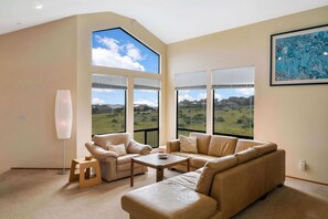 A modern living room with a large window offering a view of a green landscape and a blue sky. - Mare Vista (TOT # 2194): 2  BR, 2  BA House in The Sea Ranch, Sleeps 4 (The Sea Ranch)