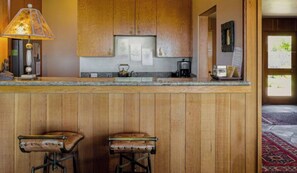 A kitchen with wooden cabinets, a bar counter, and two stools. - Autumn Mist TOT #2141: 2  BR, 2.5  BA House in The Sea Ranch, Sleeps 4 (The Sea Ranch)