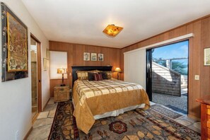 A bedroom with a bed, a nightstand, a lamp, a patterned rug, and a view of the outside. - Autumn Mist TOT #2141: 2  BR, 2.5  BA House in The Sea Ranch, Sleeps 4 (The Sea Ranch)