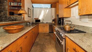 A kitchen with wooden cabinets, a stone backsplash, a large bowl, a stove, and a kettle. - Autumn Mist TOT #2141: 2  BR, 2.5  BA House in The Sea Ranch, Sleeps 4 (The Sea Ranch)