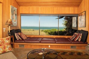 A room with a large window, a leather sofa, a glass coffee table, and a lamp. - Autumn Mist TOT #2141: 2  BR, 2.5  BA House in The Sea Ranch, Sleeps 4 (The Sea Ranch)