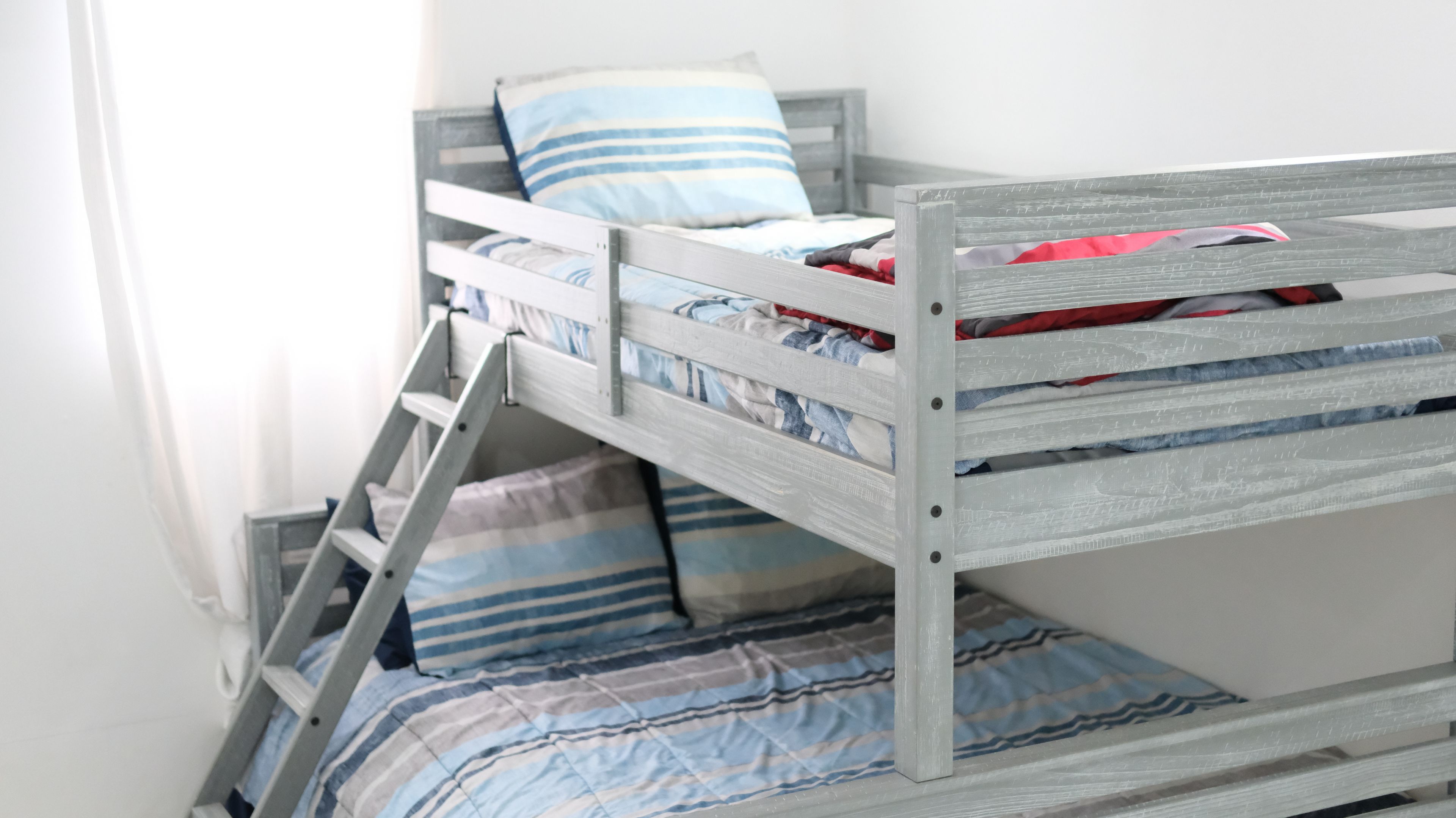 A bunk bed with a ladder, pillows, and a striped blanket.