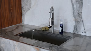 A kitchen sink with a modern faucet, a soap dish, and a bottle of dish soap.