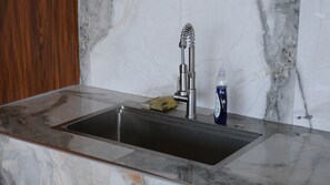 A modern kitchen with a stainless steel sink, a marble countertop, and a faucet with a flexible hose. - Casa Luna Pool House NO POOL (Coamo)