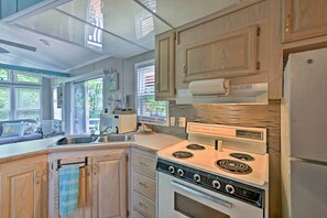 A kitchen with wooden cabinets, a stove, and a refrigerator. - Middle Bass Island Escape: Resort Pool & Bar! (Put-in-Bay)