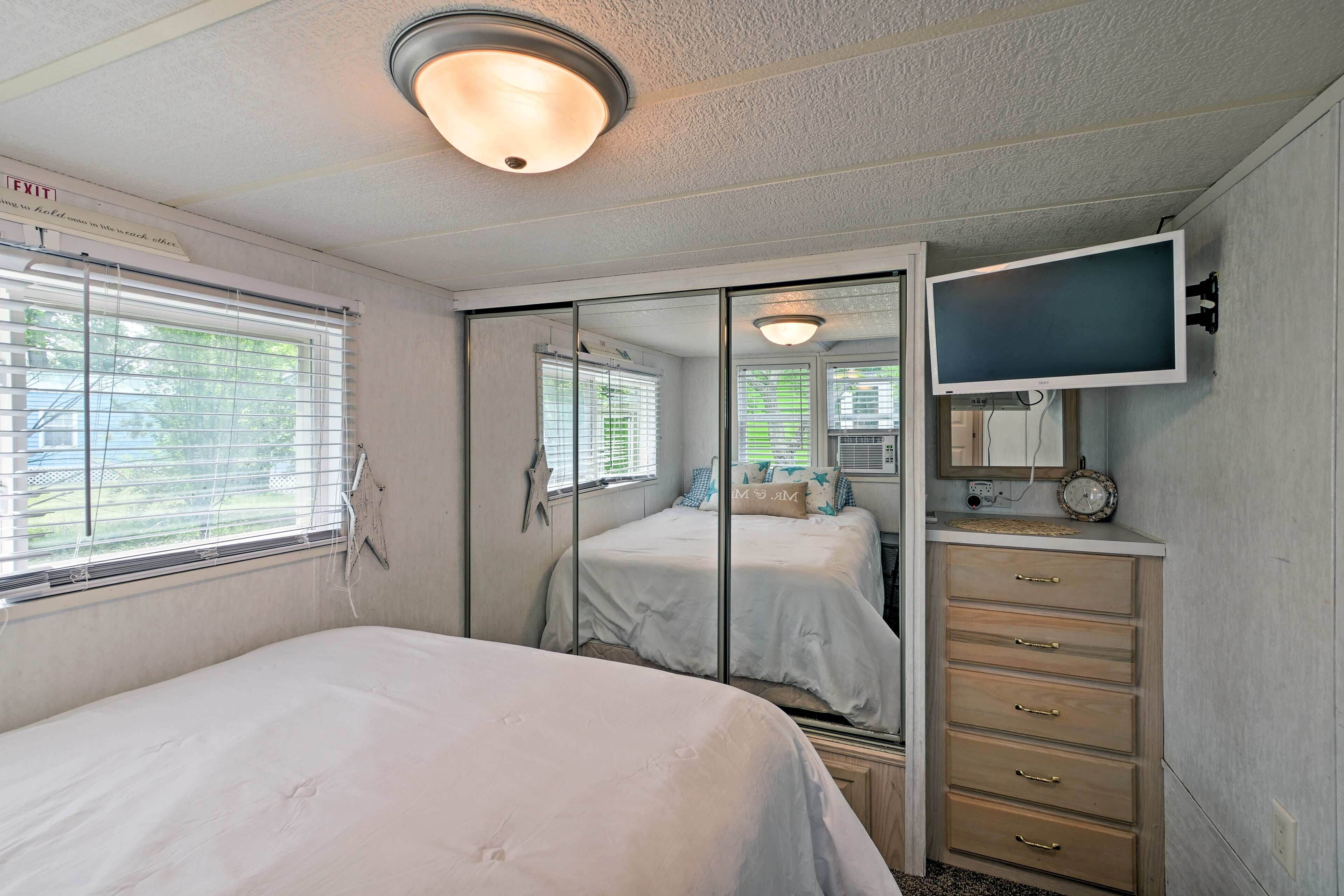 A bedroom with a bed, a dresser, a television, and a mirror.