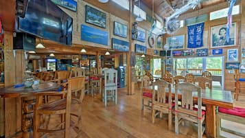 A restaurant with wooden furniture, a large TV, and various decorations on the walls.