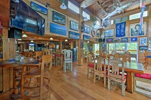 A restaurant with wooden furniture, a large TV, and various decorations on the walls.