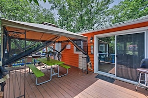 A wooden deck with picnic tables and a covered area, a sliding glass door, and a small outdoor kitchen area. - Middle Bass Island Escape: Resort Pool & Bar! (Put-in-Bay)