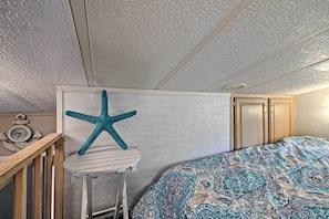 Quarto com cama, decoração em formato de estrela-do-mar, relógio e móveis de madeira.