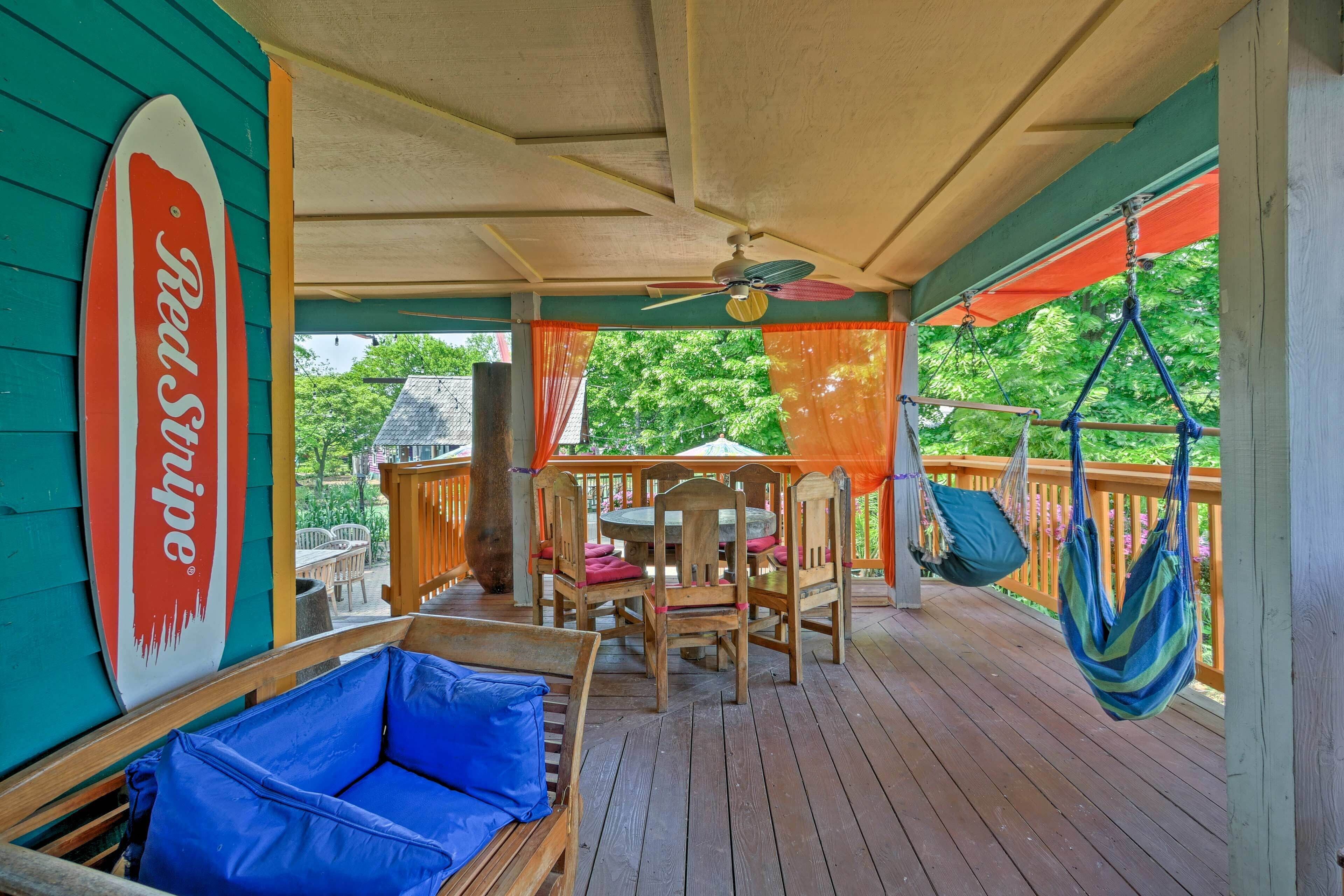 A covered outdoor deck with wooden furniture, a table, chairs, and a hammock.