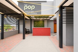 Ein Club, Pop-Disco-Bar-Lounge mit einem roten Empfangstresen, schwarz-weiß kariertem Boden und einer Wandgestaltung in Grün.