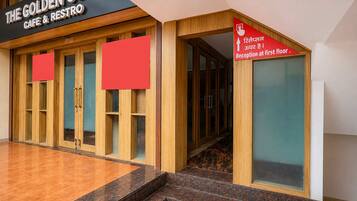 A building entrance with a sign for 'The Golden Core Cafe & Restro' and a directional sign pointing to the reception on the first floor.