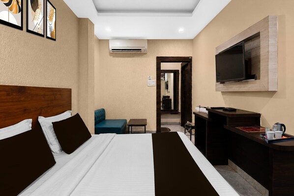 A hotel room with a bed, a desk, a chair, a television, and artwork on the wall.