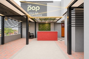 A Club Pop Disco Bar Top Lounge with a red reception desk, black and white checkered flooring, and a green wall feature. - Classic Hotel Shan (Jaipur)