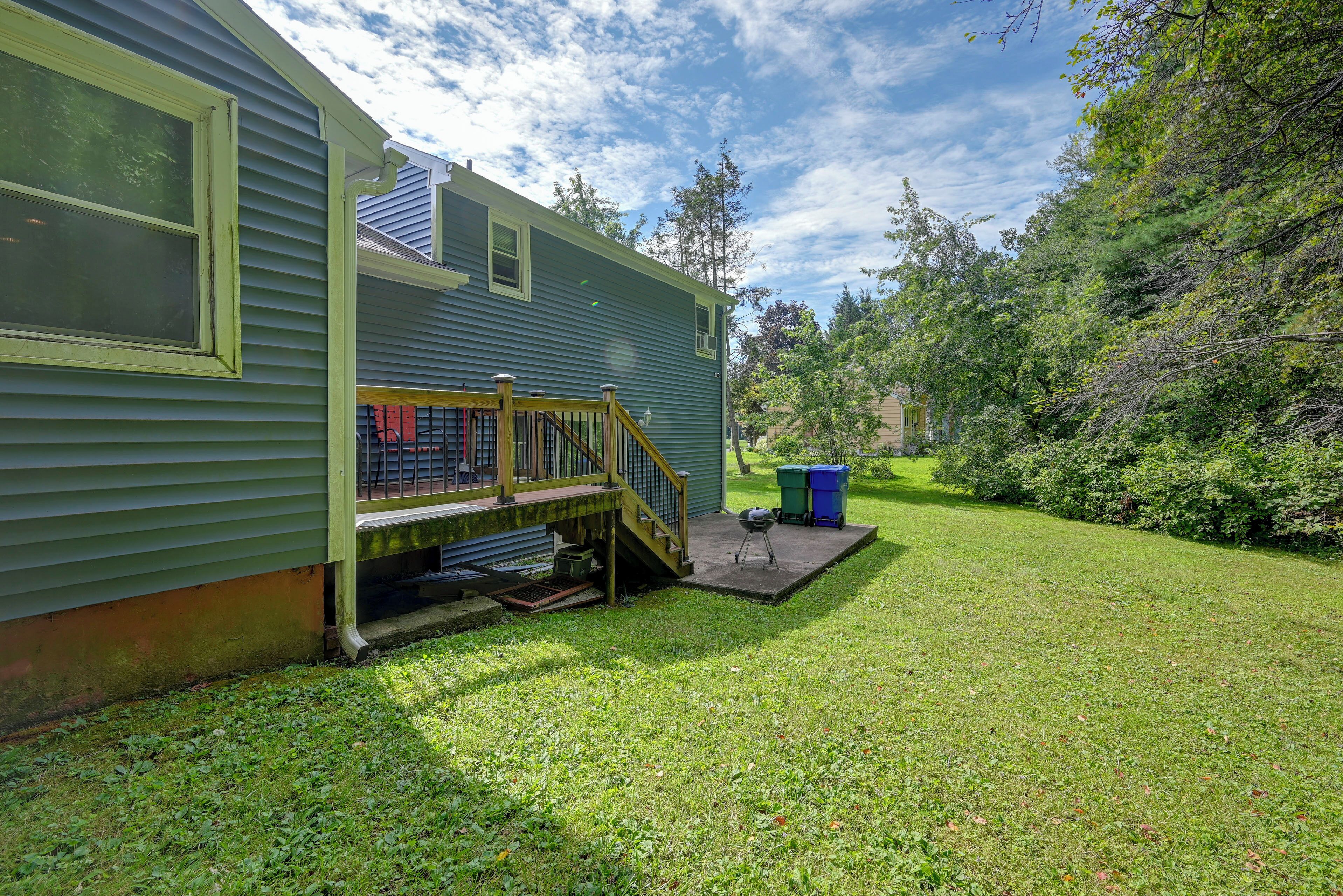 A residential property with a covered porch, a small outdoor grill, and a well-maintained lawn.
