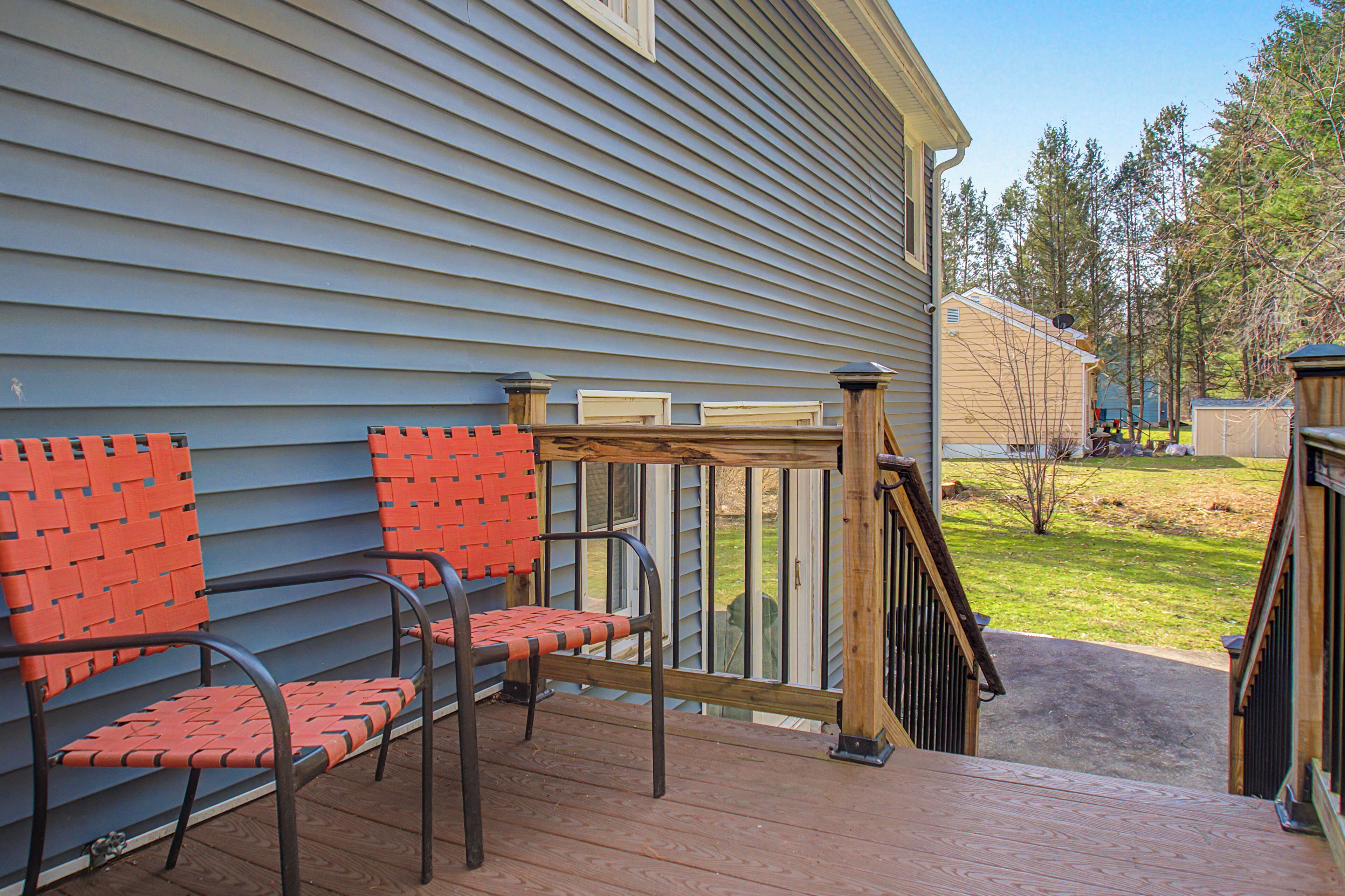Une terrasse en bois avec deux chaises rouges et une rambarde en bois.