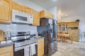 Una cocina con armarios de madera, electrodomésticos de acero inoxidable, un comedor con mesa y sillas, y una araña.