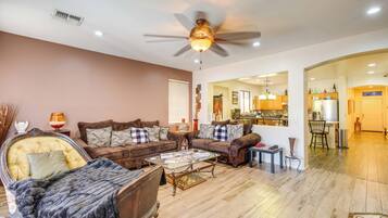 Sala de estar com ventilador de teto, sofá, mesa de centro e um tabuleiro de xadrez.