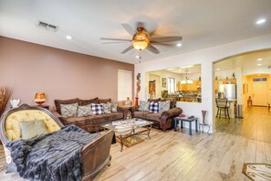 Ein Wohnzimmer mit Deckenventilator, einer Sofagarnitur, einem Couchtisch und einem Schachbrett.