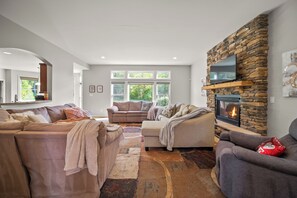 A modern living room with a stone fireplace, comfortable seating, and large windows. - < 1 Mi to Geist Park & Beach! Playroom & Patio (McCordsville)