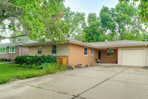 A residential house with a garage, a front yard with a lawn and shrubs, and a driveway leading to the entrance.