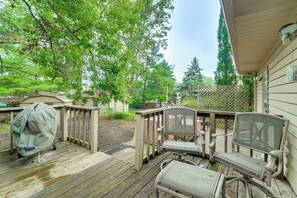 A wooden deck with outdoor furniture, a covered seating area, and a view of a residential property with trees.