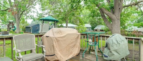 Une terrasse en bois avec des meubles d’extérieur, une table couverte et un barbecue.