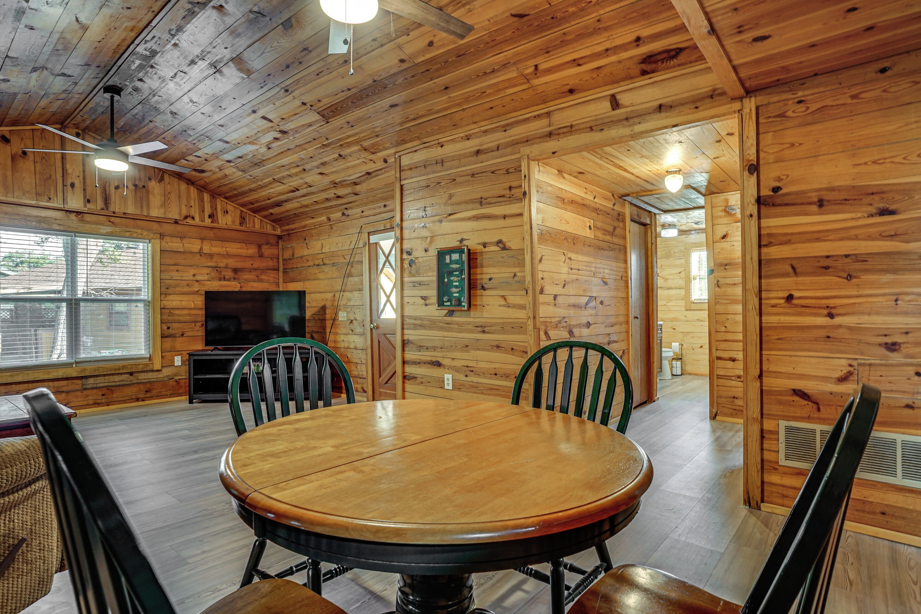A wooden interior with a round dining table, chairs, a television, and a wooden ceiling.