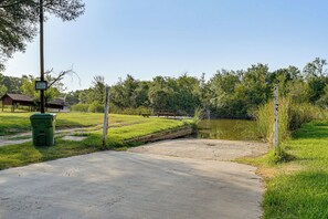 Ein Betonweg führt zu einer kleinen Holzhütte, einem Picknicktisch und einem Wegweiser in einer Parkanlage.