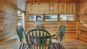 Un interior de madera con un comedor que incluye una mesa redonda y cuatro sillas.