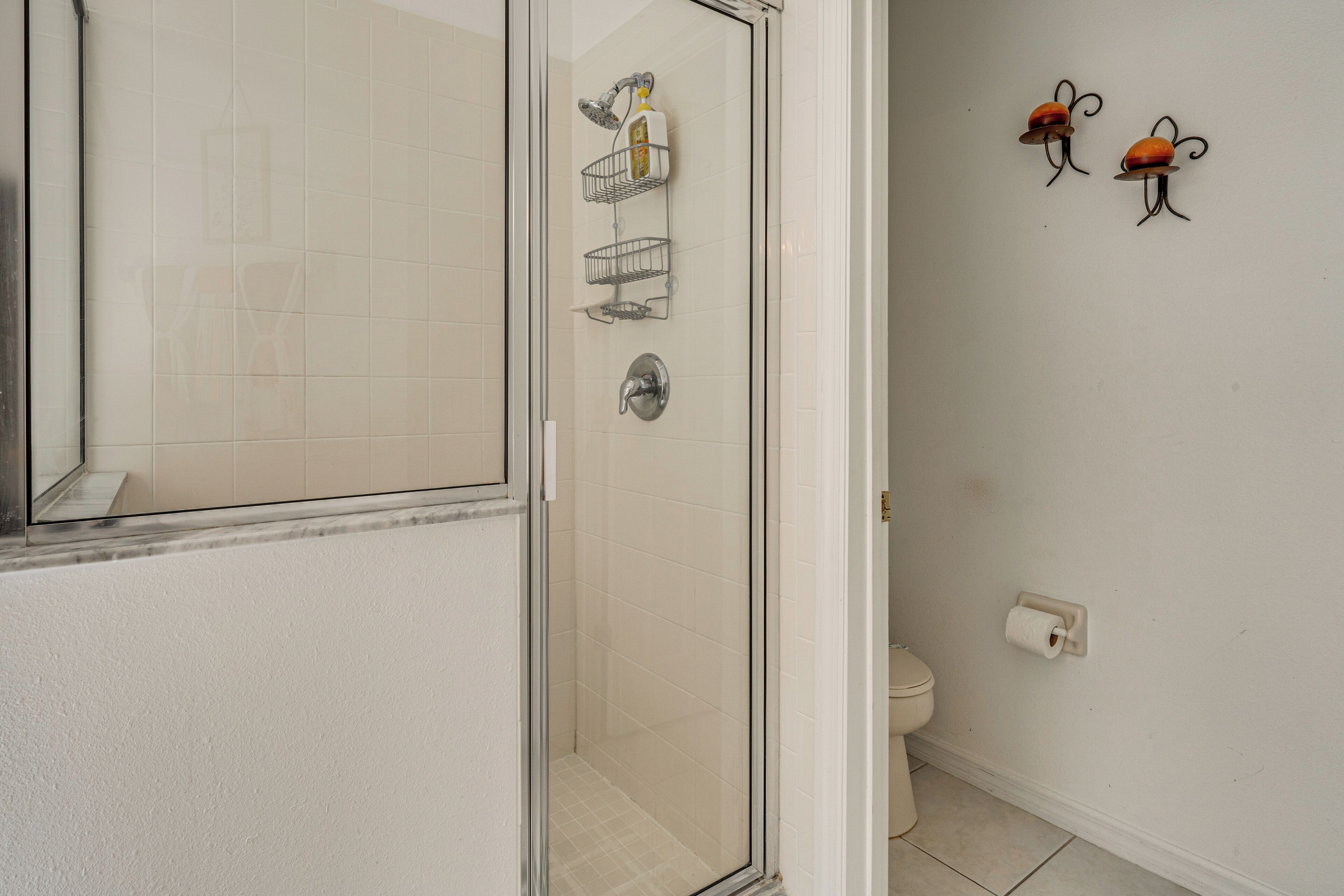 A bathroom with a glass shower enclosure, a toilet, and decorative wall art.