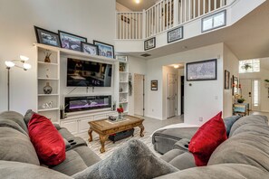 A spacious living room with a large flat-screen TV, grey sofas with red cushions, a wooden coffee table, and a staircase leading to an upper level. - 9 Mi to Disney! Family-friendly Home w/ Pool (Kissimmee)