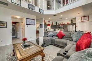 A spacious living room with a grey sectional sofa, a coffee table with decorative items, and a view into the kitchen area. - 9 Mi to Disney! Family-friendly Home w/ Pool (Kissimmee)