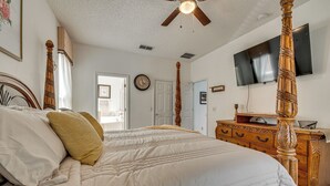 Ein Schlafzimmer mit Himmelbett, einem Holzkoffer, einem Flachbildfernseher und einem Deckenventilator.