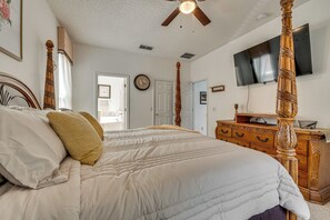 A bedroom with a four-poster bed, a wooden dresser, a flat-screen TV, and a ceiling fan. - 9 Mi to Disney! Family-friendly Home w/ Pool (Kissimmee)
