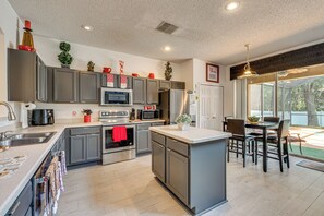 A modern kitchen with stainless steel appliances, a central island, and a dining area with a view. - 9 Mi to Disney! Family-friendly Home w/ Pool (Kissimmee)