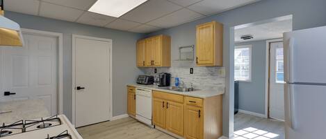 A kitchen with wooden cabinets, a white stove, and a countertop with a coffee maker.