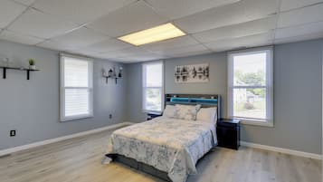 A bedroom with a bed, two nightstands, a wall-mounted shelf with decorative items, and a painting.