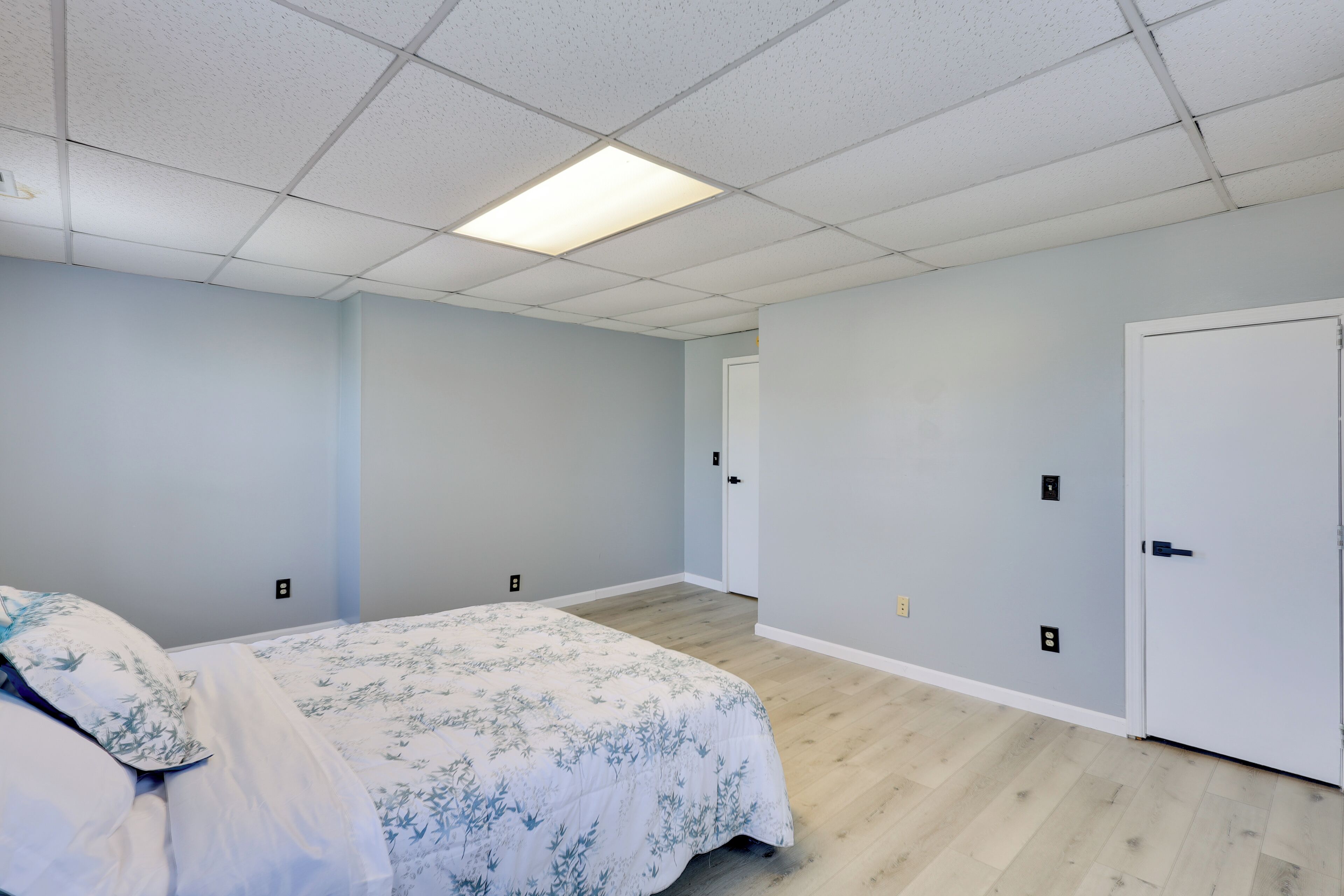 A bedroom with a bed, a door, and a light switch on the wall.
