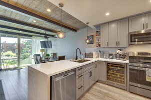 Una cocina moderna con electrodomésticos de acero inoxidable, lavavajillas y un refrigerador para vinos.