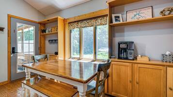 A wooden dining table with chairs, a coffee maker, and a map on the wall.